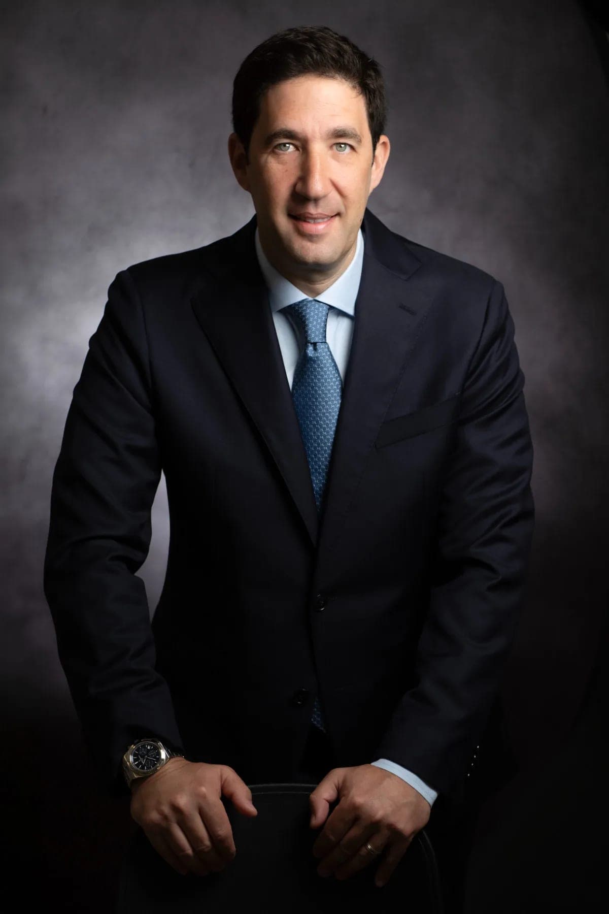 The final result: an image portrait of a client in a dark suit and blue tie on a grey backdrop — mobile studio photography by Sharon Gabay