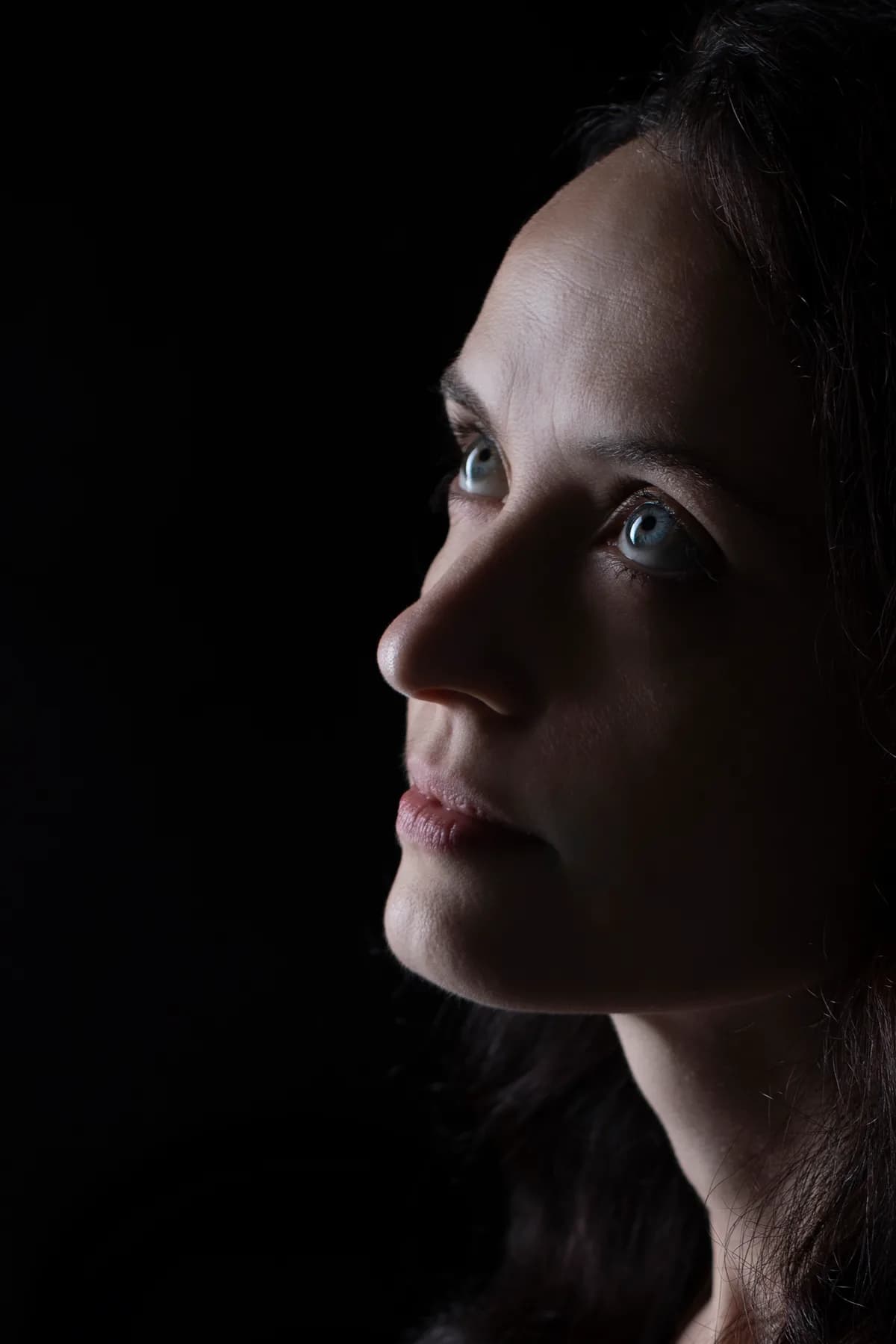Personal portrait in profile, half the face in light and the rest in deep shadow — fine-art studio photography | Photo: Sharon Gabay