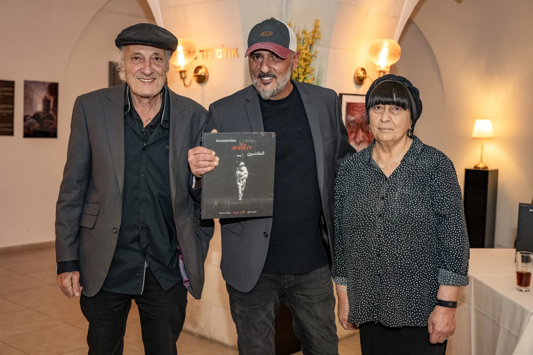 שרון גבאי אוחז את ספר הצילום ״ירושלמים״ עם הוריו בערב ההשקה בבית אות המוצר הירושלמי