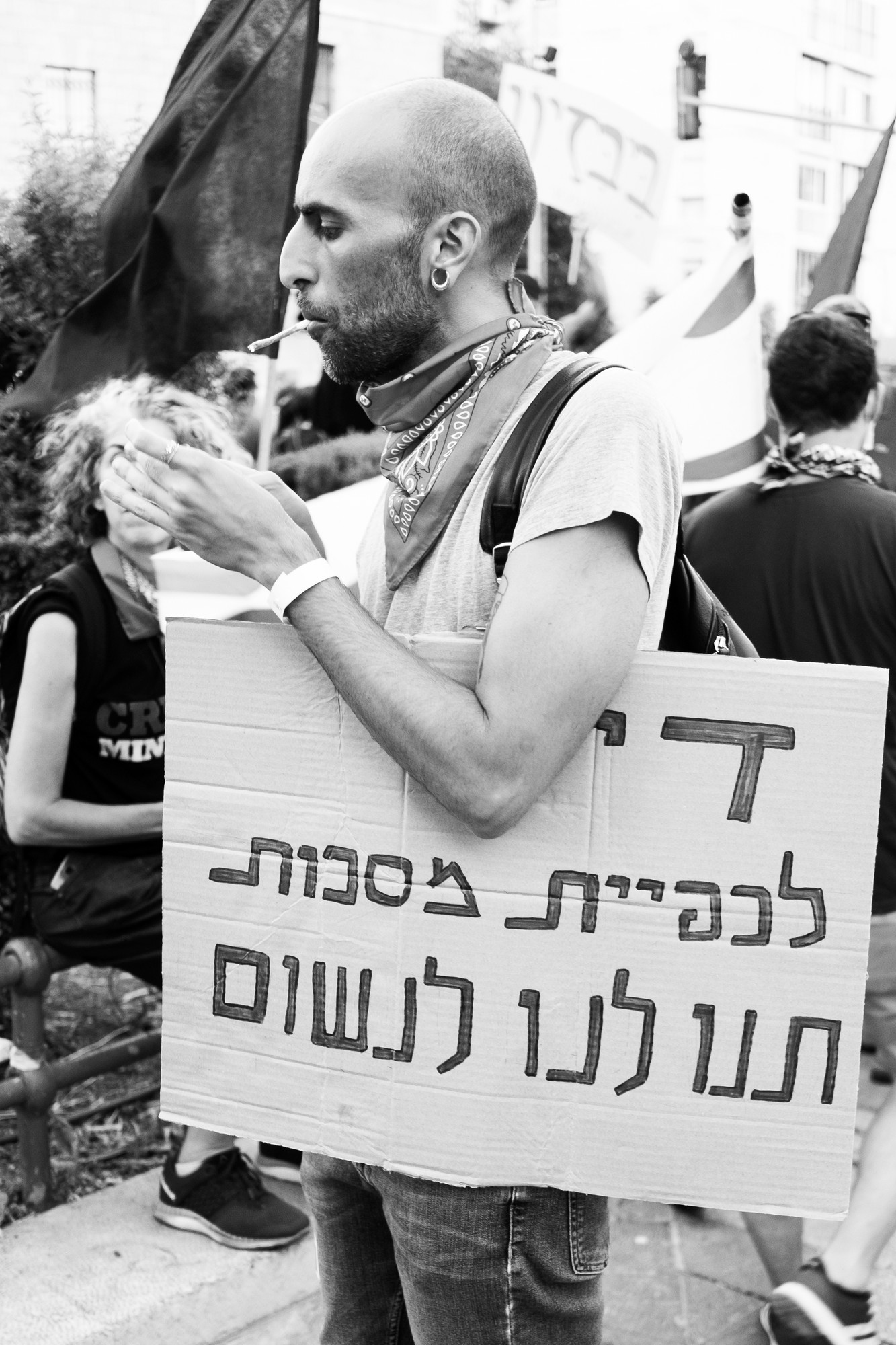 מפגין בירושלים מחזיק שלט "די לכפיית מסכות — תנו לנו לנשום" ומדליק סיגריה | צילום: שרון גבאי