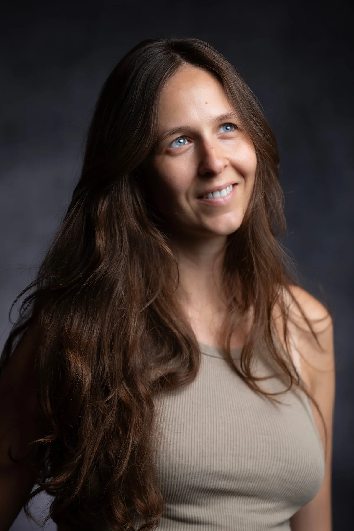 A natural headshot of a woman in a light top, long hair and a soft smile | Photo: Sharon Gabay
