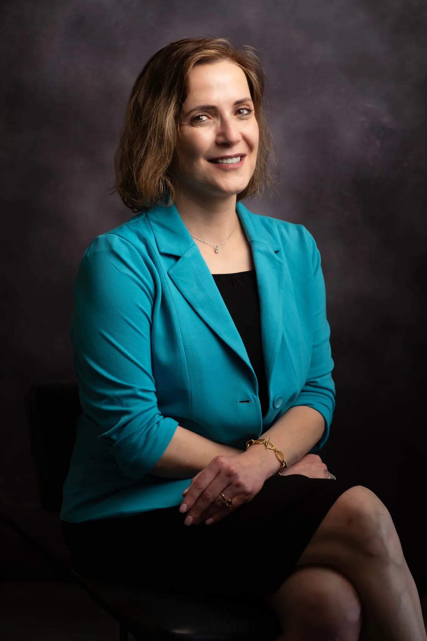 Headshot of a therapist in a turquoise blazer against a clean background, warm and approachable expression — Sharon Gabay, headshot photographer