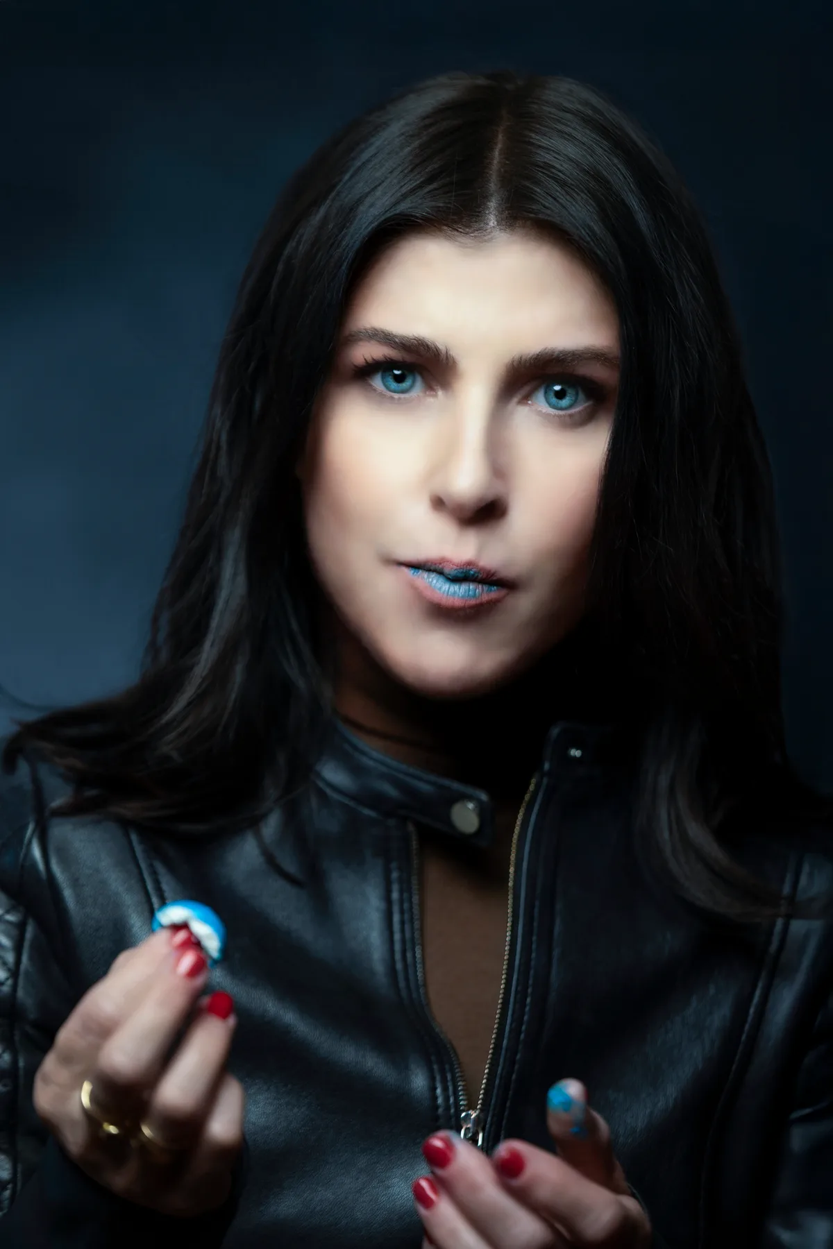 Personal portrait of a woman in a black leather jacket against a dark backdrop, direct gaze, dramatic light | Photo: Sharon Gabay