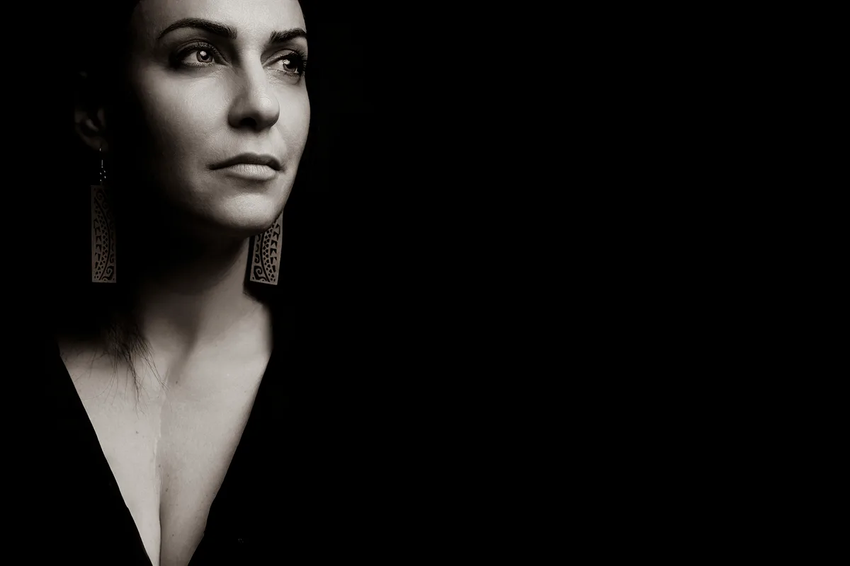 Low-key black-and-white personal portrait — a face and earrings emerging from a dark background | Photo: Sharon Gabay