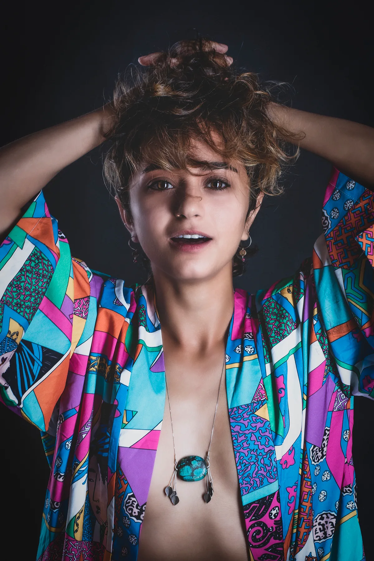 Colorful fine-art portrait of a woman in a printed kimono, hands in her hair and a direct gaze | Photo: Sharon Gabay