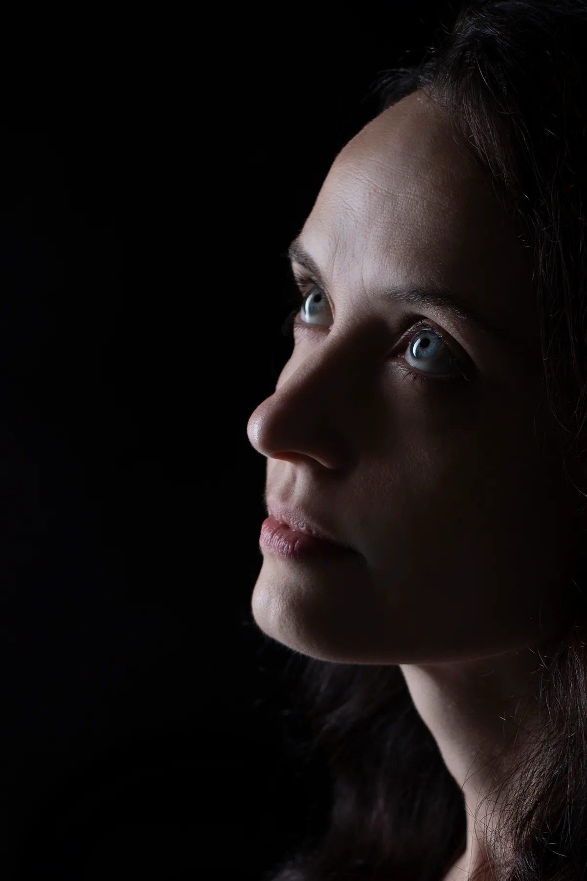Personal portrait in profile, half the face in light and the rest in deep shadow — fine-art studio photography | Photo: Sharon Gabay