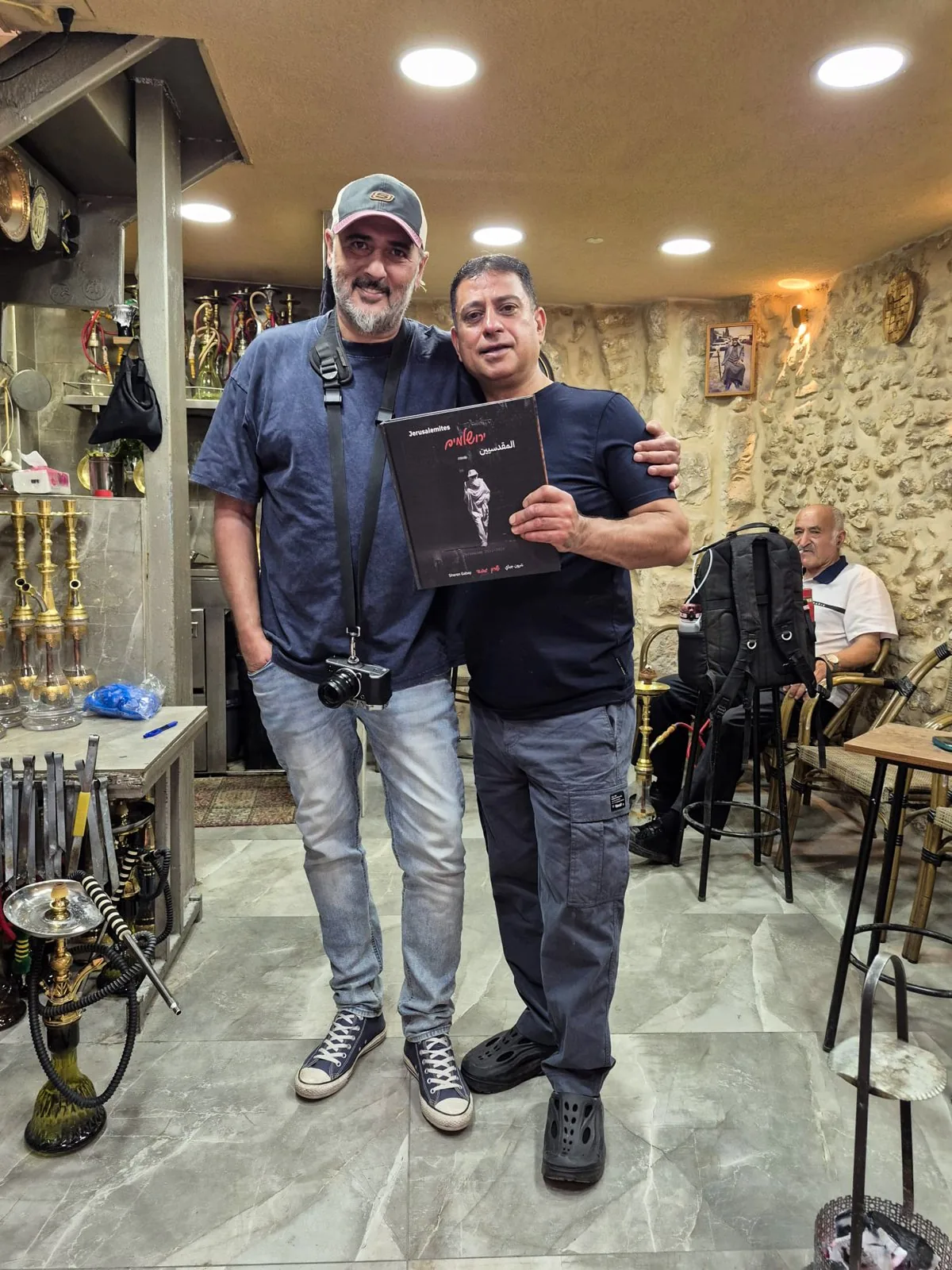 With Abu Yasser, owner of a hookah café in the Muslim Quarter of Jerusalem's Old City, holding JERUSALEMITES.